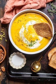 a bowl of carrot soup with bread on the side