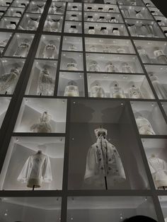 a display case filled with lots of mannequins in white outfits and dresses