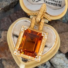 This fantastic pendant is centered with an emerald cut citrine, weighing 8.91 carats, in a four-prong setting. The corners are each bead set with four (4) round brilliant cut diamonds. The pendant measures 33.3mm long, including the bail, by 15.9mm wide by 11.4mm deep and hangs on an 18-inch long wheat link chain that is finished with a lobster claw clasp. Luxury Custom Yellow Gold Gemstone Necklace, Luxury Emerald Cut Gemstone With 17 Jewels, Exquisite Formal Gemstone Pendant, Exquisite Formal Pendant Gemstones, Exquisite Pendant Gemstones For Formal Occasions, Luxury Citrine Gemstones With Accents, Formal Rectangular Fine Jewelry Gemstones, Elegant Jewel Pendant Gemstones, Elegant Yellow Diamond Gemstones