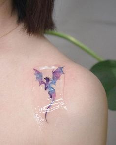 a woman with a tattoo on her shoulder has a purple dragon painted on it's back