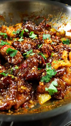 a pan filled with meat and veggies covered in sauce, garnished with parsley