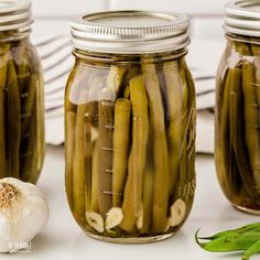 three jars filled with pickled green beans and garlic