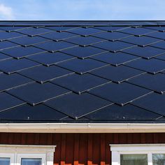 an image of a roof that has solar panels on it and windows in the background