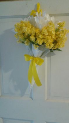 a bouquet of yellow and white flowers hanging on a door