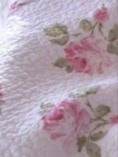 a bed with pink roses on it and white sheets