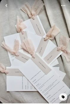 several pieces of paper with ribbons tied to them on top of a sheet of cloth