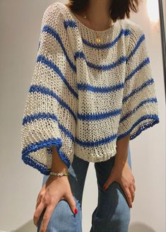 a woman is standing in front of a mirror with her hand on her hip and wearing a blue and white striped sweater