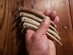 a hand is holding several pieces of wood with metal hooks on the top and bottom