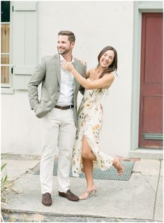 a man standing next to a woman in a dress on the sidewalk near a building