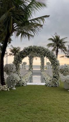 an outdoor ceremony setup with white flowers and greenery on the grass, overlooking the ocean