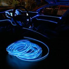 the interior of a car is lit up with blue neon lights and steering wheel covers