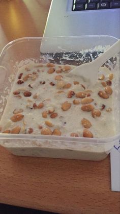 a plastic container filled with food sitting on top of a wooden table next to a laptop computer