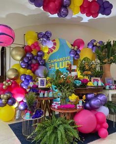 balloons are hanging from the ceiling in front of tables with plants and gifts on them