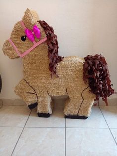 a horse made out of straw sitting on top of a tile floor next to a wall