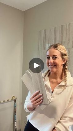 a woman is smiling while holding some papers