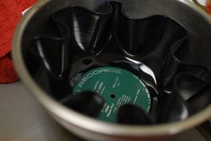 a close up of a metal container with black plastic cups in it and a red towel on the side