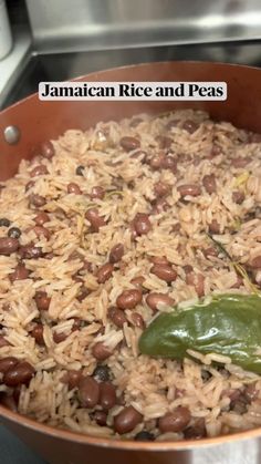 a pot filled with rice and beans next to a green pepper on top of a stove