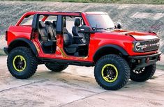 a red truck with yellow wheels parked on concrete