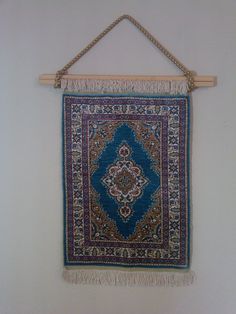 a blue rug hanging on a wall with a wooden hanger and two hooks holding it