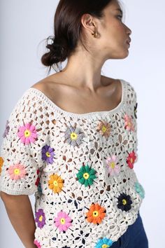 a woman wearing a white crochet top with colorful flowers on the front and sides