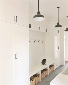 a hallway with white cabinets and hanging lights