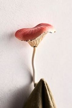 a mushroom shaped object hanging on the wall next to a cloth bag with a toothpick sticking out of it