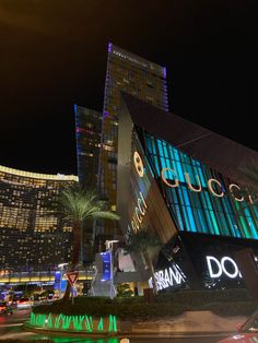 an illuminated building in the middle of a city at night with palm trees and buildings lit up