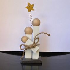 a small wooden sculpture with balls and a star on it's top, sitting on a black table