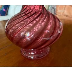 a red glass vase sitting on top of a wooden table