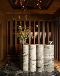 three vases with flowers in them sitting on a marble floor next to a wall