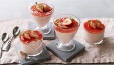 three desserts with strawberries on top and spoons next to eachother