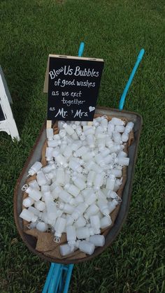 a bowl full of ice cubes sitting on top of green grass next to a sign