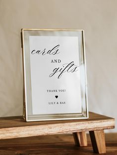 a card and gift box sitting on top of a wooden table next to a white wall