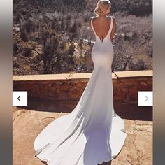 a woman in a long white dress looking out at the mountains and trees, with her back turned to the camera