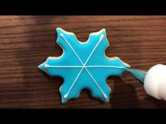 a cookie decorated with blue icing and white piping on top of a wooden table