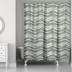 a bathroom with a shower curtain that has wavy waves on it, along with a white dresser and mirror