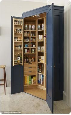 an open pantry cabinet in the corner of a room next to a stool and table