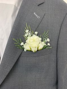 a man wearing a gray suit with white flowers in his lapel