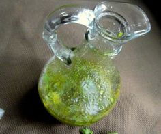 a glass pitcher filled with green liquid sitting on top of a table next to a small piece of parsley