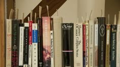 a row of books sitting on top of a wooden book shelf next to a stair case