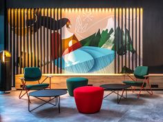 colorful chairs and tables are in front of a wall with an abstract painting on it