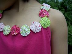 a woman wearing a pink top with colorful flowers on the back of her neckline