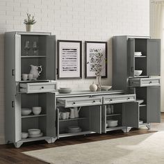 a dining room with gray cabinets and white dishes on the counter top in front of a brick wall