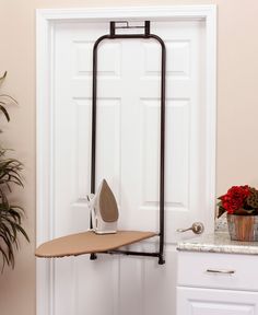 an ironing board is hanging on the wall next to a potted plant and shoe rack