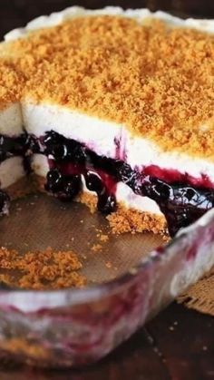 a pie with blueberries and crumbs in it sitting on a wooden table