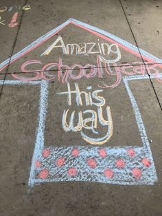 chalk drawing on the sidewalk saying amazing school year this way with a house and flowers