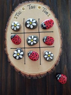 a wooden board topped with lots of rocks covered in ladybugs and daisies