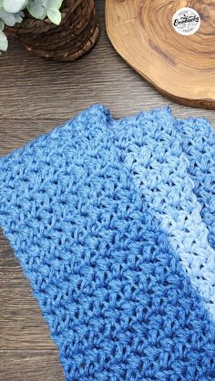 a blue crocheted dishcloth sitting on top of a wooden table next to a potted plant