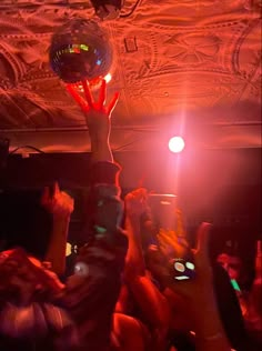 people are holding up their cell phones in the air at a party with disco balls