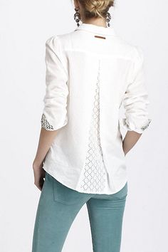 the back of a woman's shirt with an open collar and lace detailing on it